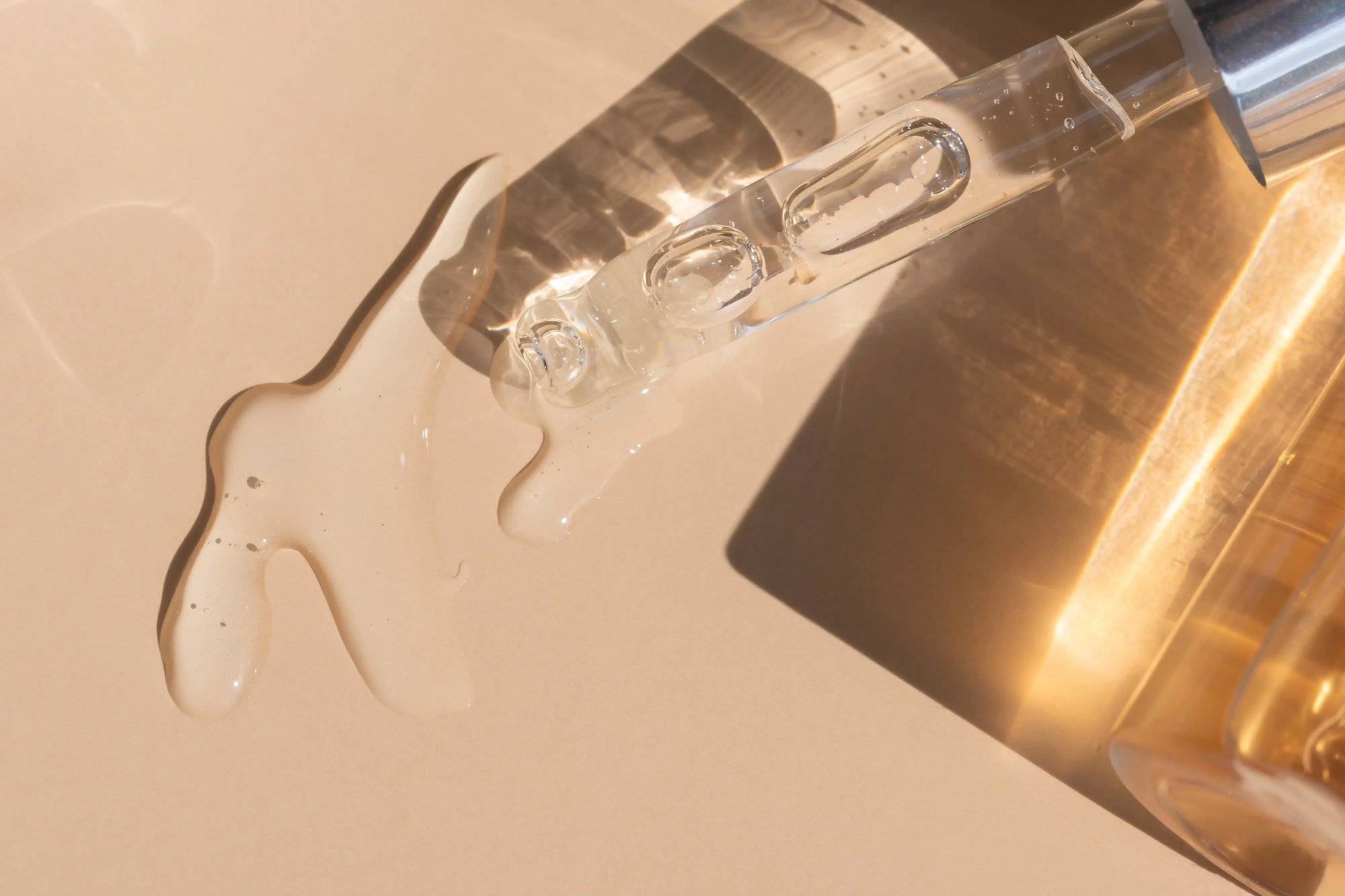close-up-pouring-liquid-serum-with-golden-bottle