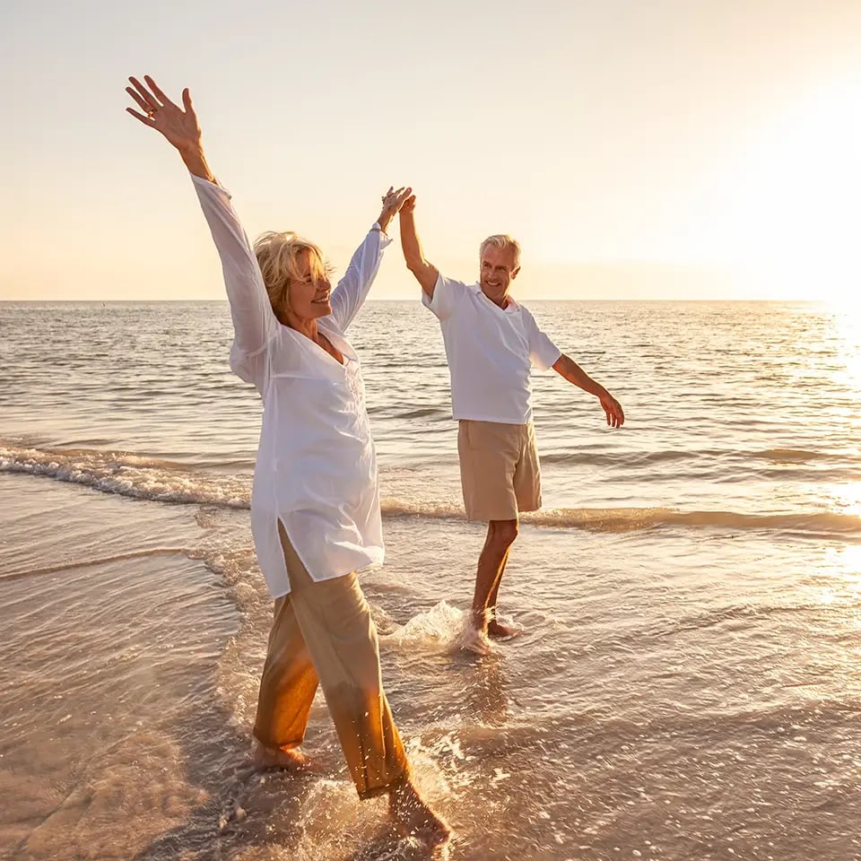 senior-couple-happy-walking-holding-hands_beach-sunset_960px